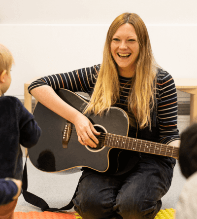 A woman playing the guitar for a child.